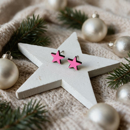 Sterne-Ohrstecker aus Holz in Neonpink auf einem weißen Holzstern mit Tannengrün