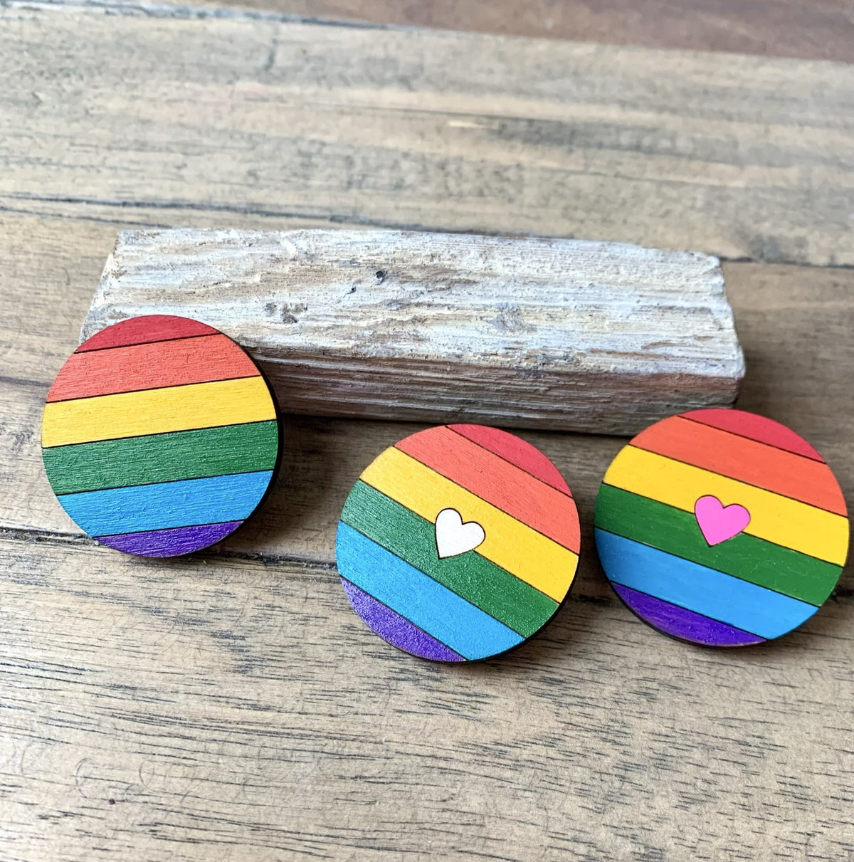 Drei Regenbogen-Broschen aus Holz: klassisch, mit Herz in Natur und mit Herz in Neonpink