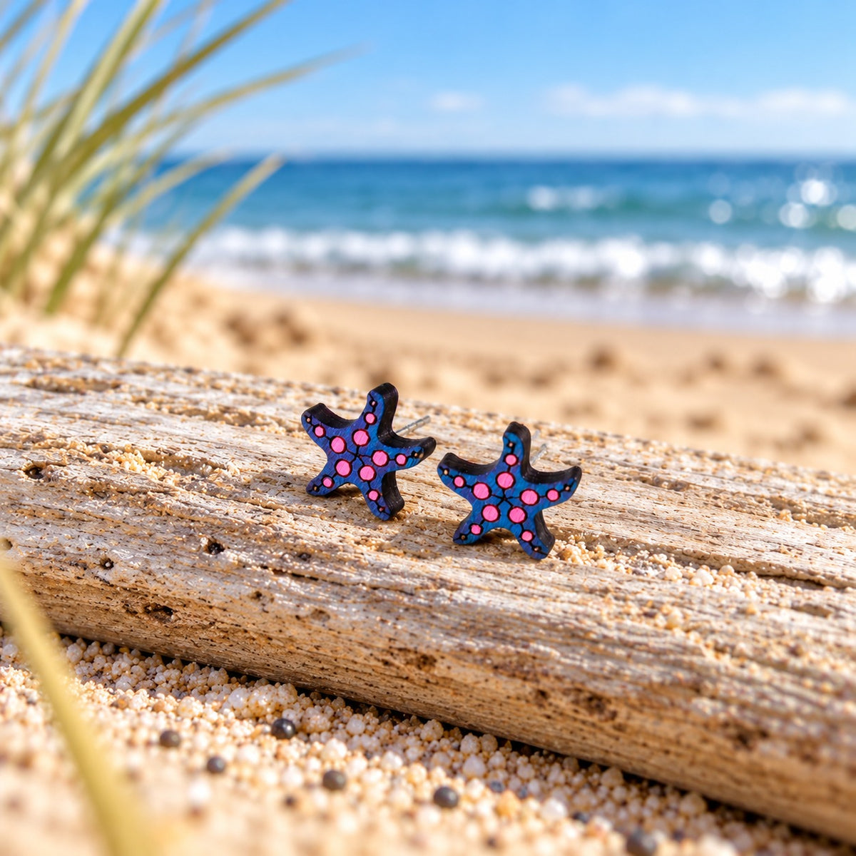 Seestern-Ohrstecker aus Holz in Marine und Neonpink auf Treibholz am Strand