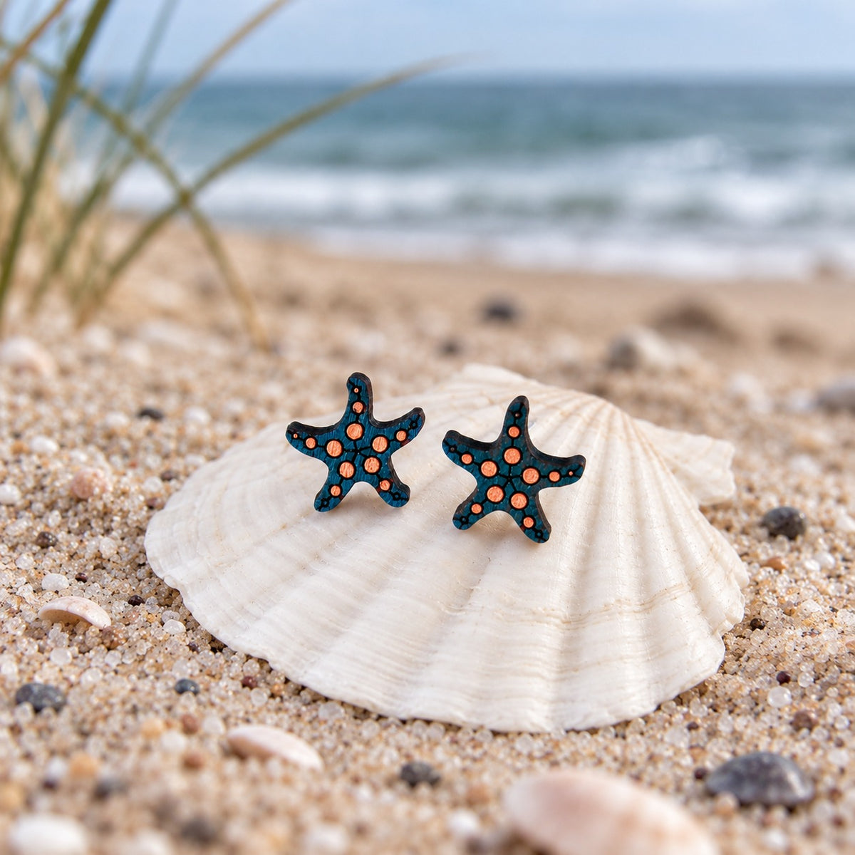 Seestern-Ohrstecker aus Holz in Türkis mit neonorangen Punkten auf einer Muschel am Strand
