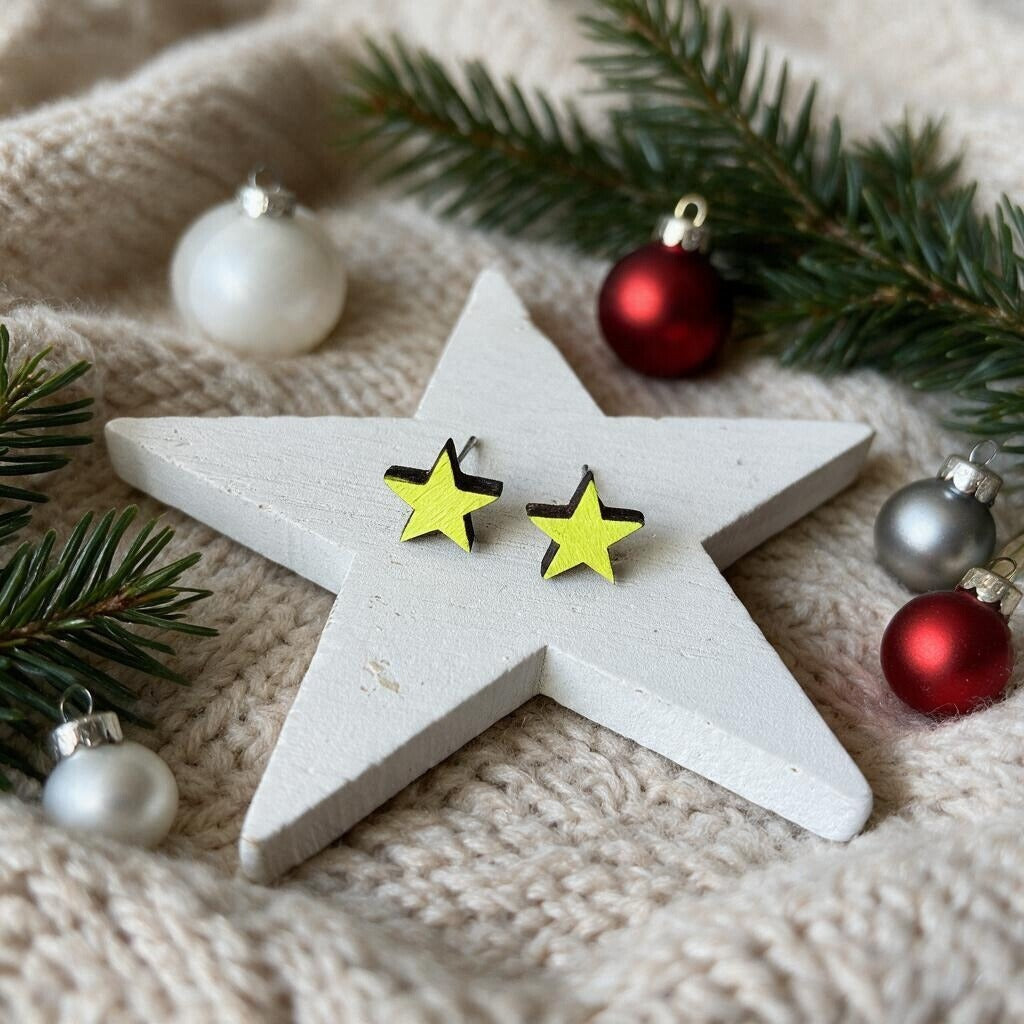 Sterne-Ohrstecker aus Holz in Neongelb auf einem weißen Holzstern mit Christbaumkugeln