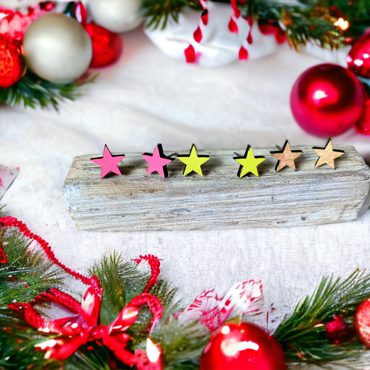 Sterne-Ohrstecker aus Holz in Neonpink, Neongelb und Gold auf Treibholz mit Weihnachtsdeko